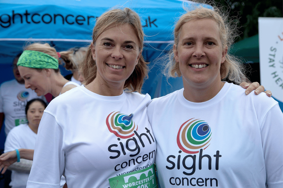 2 ladies wearing sight concern tshirts, smiling for the camera
