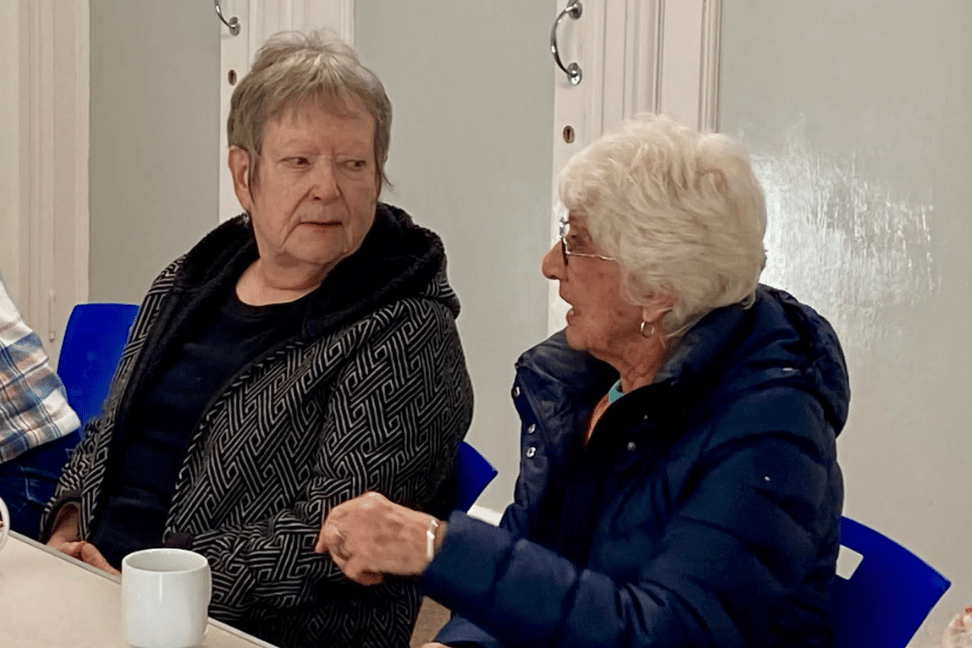 Two ladies sat chatting over a cup of tea