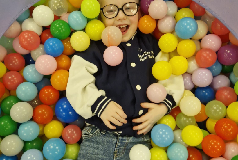 a young boy laughing in a ball pit